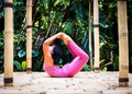 Yoga practice outdoor. Asian yoga teacher practicing Dhanurasana, Bow Pose. Backbending asana in hatha yoga. Self care concept.