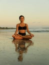 Yoga retreat. Asian woman practicing Lotus pose. Padmasana. Hands in gyan mudra. Closed eyes. Water reflection. Yoga on the beach Royalty Free Stock Photo