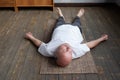Yoga. Senior man meditating on a wooden floor and lying in Shavasana pose. Royalty Free Stock Photo