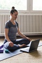 Yoga student doing online fitness lesson on laptop at home