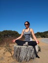 Yoga Superstar lady sits on tree stump, meditates