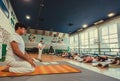 Yoga teacher explaining asanaa for active people in sport studio, training class