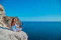Yoga time. Meditation. Contemplation. Female sitting in stylish outfit. Lady meditating on nature. Stunning seascape