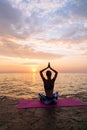 Young woman practicing yoga, sitting on pier, near the sea Royalty Free Stock Photo