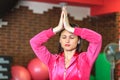 Yoga training. Beautiful white girl in a pink sports suit meditates on the yoga class at the fitness center. Royalty Free Stock Photo