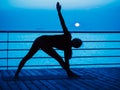 Yoga under full moon over night ocean or sea beach. Young woman`s meditation during practice. Royalty Free Stock Photo