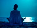 Yoga under full moon over night ocean or sea beach. Young woman's meditation Royalty Free Stock Photo