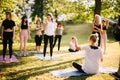 Yoga woman coach welcomes his students and gives instructions in park at dawn