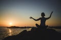 A yoga woman meditates on the ocean during sunset. Royalty Free Stock Photo