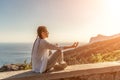 Yoga woman mountains. Profile of a woman doing yoga in the top of a cliff in the mountain. Woman meditates in yoga asana Royalty Free Stock Photo