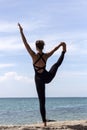 Yoga woman poses on beach near sea and rocks