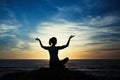 Woman silhouette sitting in Lotus position on the shore of the evening ocean Royalty Free Stock Photo