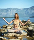Yoga woman sitting in Lotus pose. Breathing exercises and meditation at mountain lake Royalty Free Stock Photo