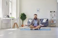 Yoga work at home. Funny fat man practices yoga meditation while sitting on the floor in the room online at home. Royalty Free Stock Photo