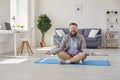 Yoga work at home. Funny fat man practices yoga meditation while sitting on the floor in the room online at home. Royalty Free Stock Photo