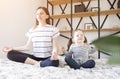 Yoga. Young woman and small daughter doing yoga lotus position in bed. relaxation and meditation at home in isolation Royalty Free Stock Photo