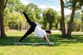 Yoga. A young woman stands in the pose of a dog looking down, doing yoga in the Park on the grass. The concept of healthy Royalty Free Stock Photo