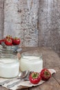 Yoghurt in a glass and a bucket with fresh strawberries on a woo Royalty Free Stock Photo