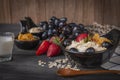 Yoghurt mix oatmeal, strawberry and grape topping in black bowl on wood table with Blue and white striped fabric, spoon,