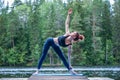 Yogi girl practicing yoga, doing Utthita Trikonasana exercise, extended triangle pose on the lake. The concept of appeasement,