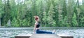 Yogi girl practicing yoga, sitting in Staff exercise, Dandasana pose on the lake. The concept of appeasement, healthy