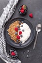 Yogurt with baked granola and berries in black ceramic plate on dark stone background. Healthy breakfast. Vertical photo Royalty Free Stock Photo