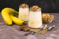 Yogurt with banana and granola on a gray table. The concept of healthy and delicious desserts.