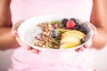 Yogurt, blackberry muesli, raspberries, blueberries, kiwi and peaches in a white bowl holding young woman Royalty Free Stock Photo