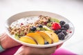 Yogurt, blackberry muesli, raspberries, blueberries, kiwi and peaches in a white bowl