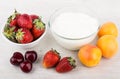 Yogurt, bowl with strawberries, apricots and cherries on table Royalty Free Stock Photo