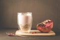 Yogurt. Yogurt with cereals, garnet and mint in glass and pomegranate fruit on a wooden tray. Dark backgtound table. Selective