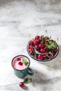 Yogurt with cherry, mint and and fresg berries on a light concrete background. Summer healthy dessert with berries