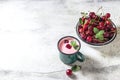 Yogurt with cherry, mint and and fresg berries on a light concrete background. Summer healthy dessert with berries