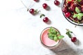 Yogurt with cherry, mint and and fresg berries on a light concrete background. Summer healthy dessert with berries