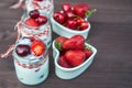 Yogurt with Cherry and strawberries, square. Berries of blueberries and strawberries are scattered on the table.