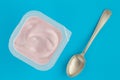 Yogurt cup with strawberry yoghurt in small plastic cup and vintage silver spoon on bright blue background - top view photo Royalty Free Stock Photo