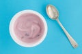 Yogurt cup with strawberry yoghurt in small plastic cup and vintage silver spoon on bright blue background - top view photo Royalty Free Stock Photo