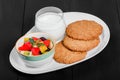 Yogurt with fruit salad and oat cookies on plate on dark wooden background. Fresh healthy breakfast. Royalty Free Stock Photo