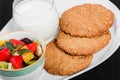 Yogurt with fruit salad and oat cookies on plate on dark wooden background. Fresh healthy breakfast Royalty Free Stock Photo