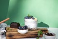 Yogurt in a glass jar with granola, chocolate, blueberries and honey on a wooden board on a green background with mint Royalty Free Stock Photo