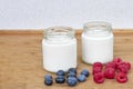 Yogurt in glass jar, raspberries and blueberries on a wooden background - close up Royalty Free Stock Photo