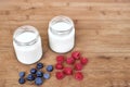 Yogurt in glass jar, raspberries and blueberries on a wooden background - from the top Royalty Free Stock Photo