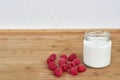 Yogurt in glass jar and raspberries on a wooden background. Royalty Free Stock Photo