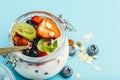 Yogurt with granola, fresh berries and nuts in a jar on a blue background. Healthy breakfast and milk dessert concept Royalty Free Stock Photo