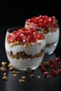 Yogurt with granola and pomegranate fruits in a glass cup on a black wooden table. Tasty dessert Healthy breakfast Royalty Free Stock Photo