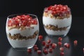 Yogurt with granola and pomegranate fruits in a glass cup on a black wooden table. Tasty dessert Healthy breakfast Royalty Free Stock Photo