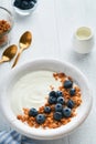 Yogurt. Greek Yogurt with granola and fresh blueberries in white bowl over old white wood background. Morning breakfast concept. H Royalty Free Stock Photo