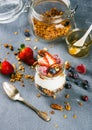 Yogurt oat granola with fresh berries, nuts, honey and mint leaves in glass jar on grey concrete textured backdrop Royalty Free Stock Photo