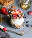 Yogurt oat granola with fresh berries, nuts, honey and mint leaves in glass jar on grey concrete textured backdrop Royalty Free Stock Photo