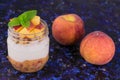 Yogurt with peach in jars on a dark background. Close-up.